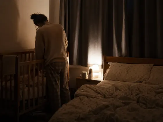 cot beside a double bed, curtains drawn