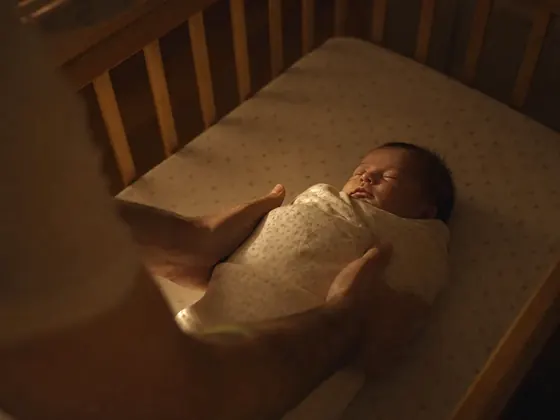 hands lowering a baby into a cot
